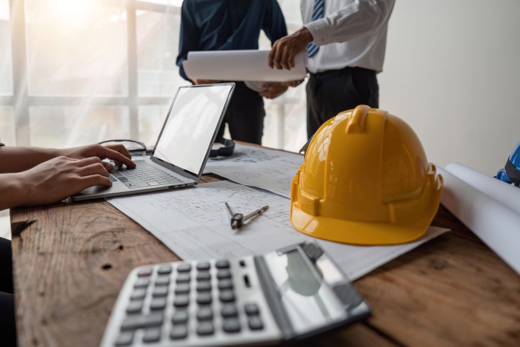 Team of engineers meeting to report project construction on laptop screen.