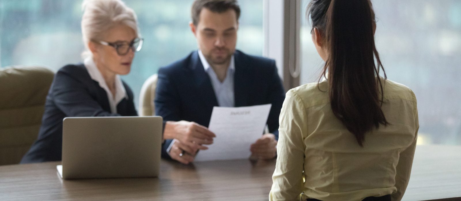 Back view of female candidate apply for position, interview in modern office, recruiters consider applicant candidature, reading resume, HR managers look through employee cv. Hiring concept