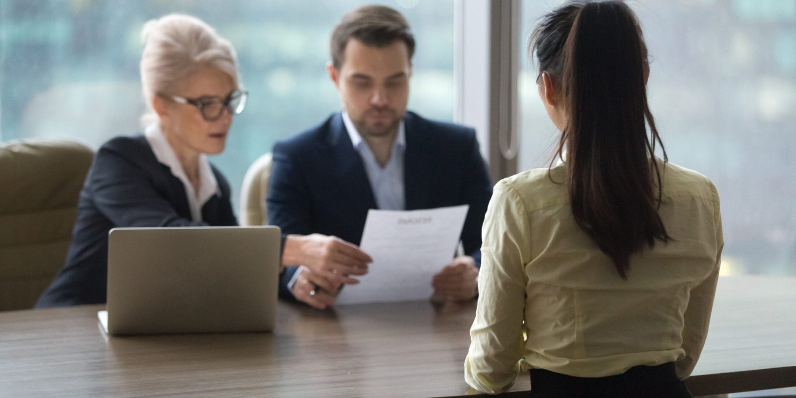 Back view of female candidate apply for position, interview in modern office, recruiters consider applicant candidature, reading resume, HR managers look through employee cv. Hiring concept