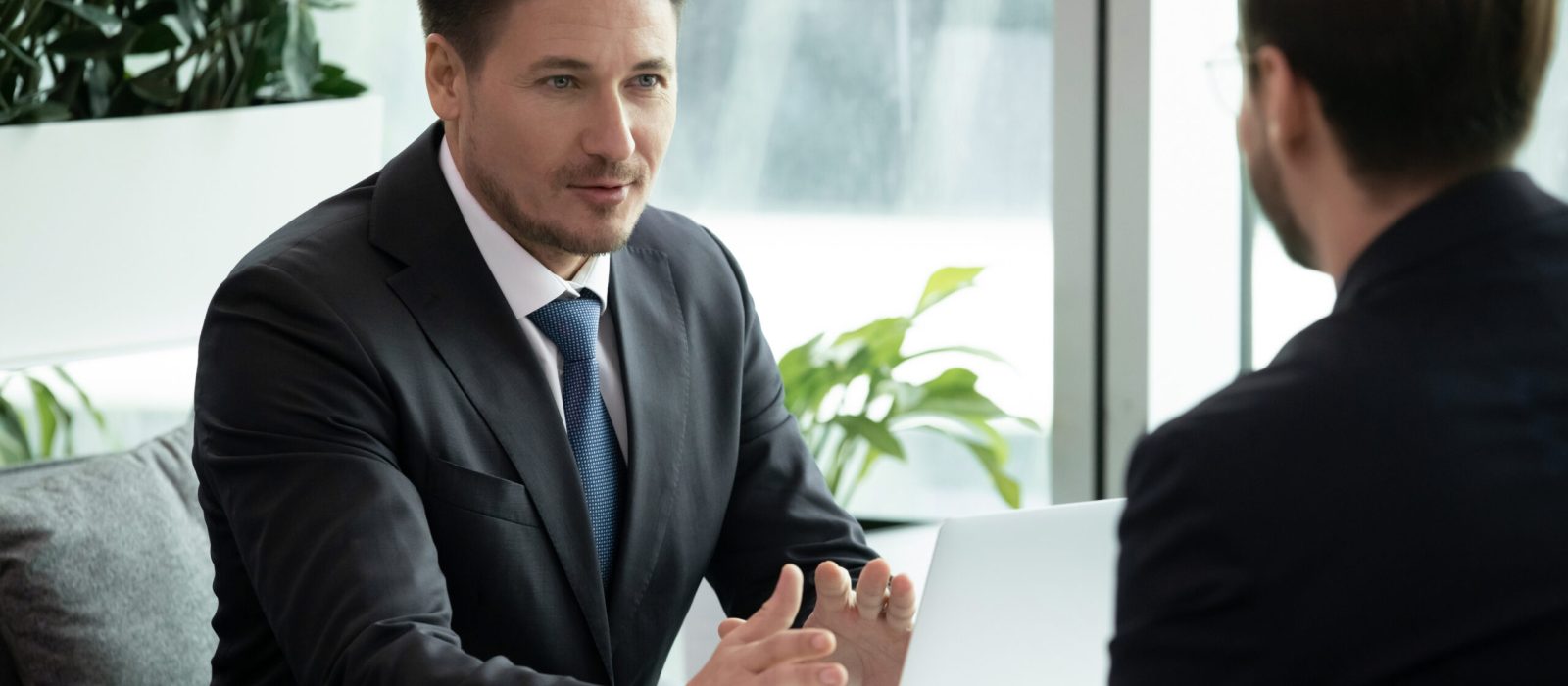 Two businessmen meet in office room sitting at table talking solving issues working on project, client and bank manager negotiating about loan lending possibility, job interview hiring process concept