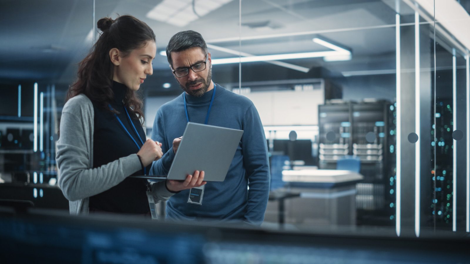 Portrait of Two Female and Male Engineers Using Laptop Computer to Analyze and Discuss How to Proceed with the Artificial Intelligence Software. Casually Chatting in High Tech Research Office