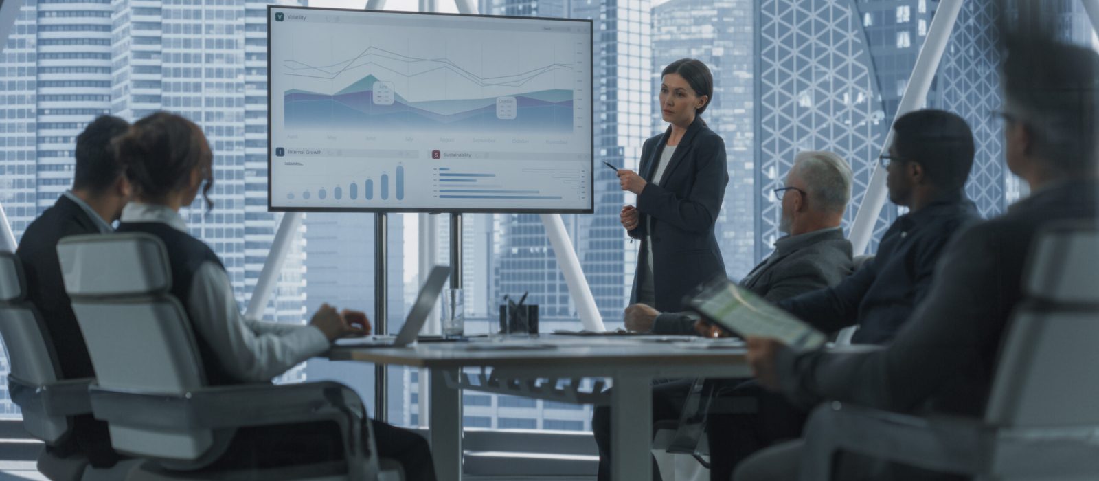 Office Conference Room Presentation: Businesswoman Talks, Uses TV Screen to Show Company Growth with Big Data Analysis, Graphs, Charts, Infographics. e-Commerce Business Concept. Dramatic Evening Edit
