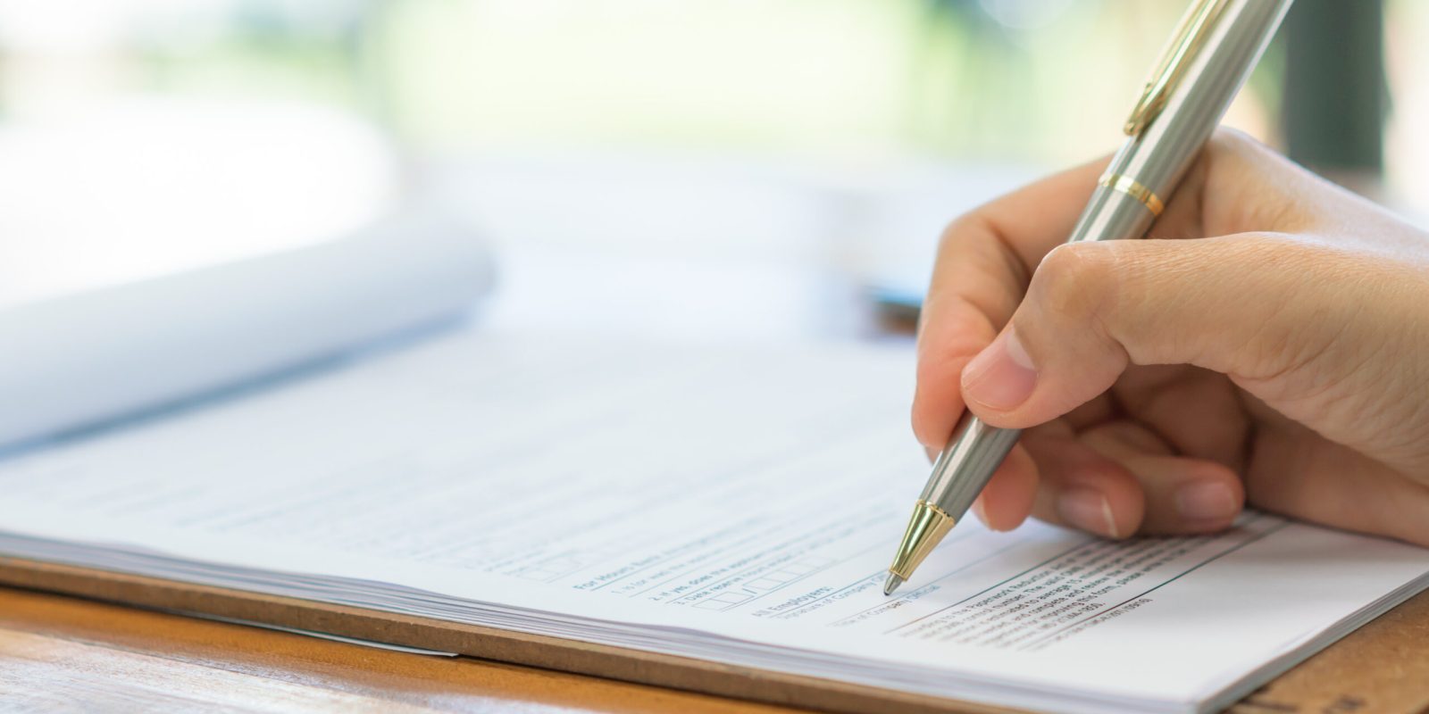 Hand with pen over application form